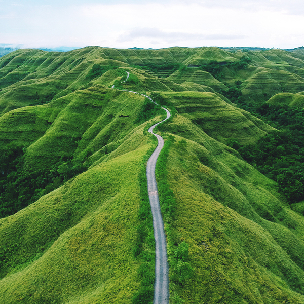 A long winding road between hills of green grass in remote parts of the Indonesian island of Sumba