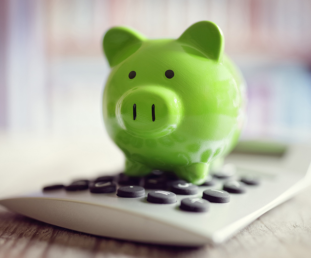 Green piggy bank on a calculator 